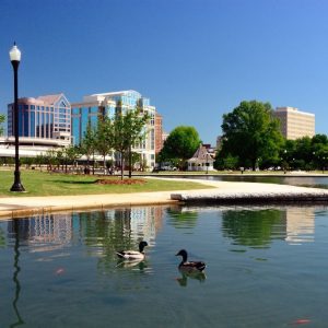 Downtown city park with pond and modern buildings in Alabama.