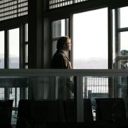 Man standing by large window looking out thoughtfully.
