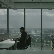 Professional working alone at office desk with city skyline view.