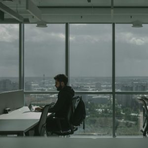 Professional working alone at office desk with city skyline view.